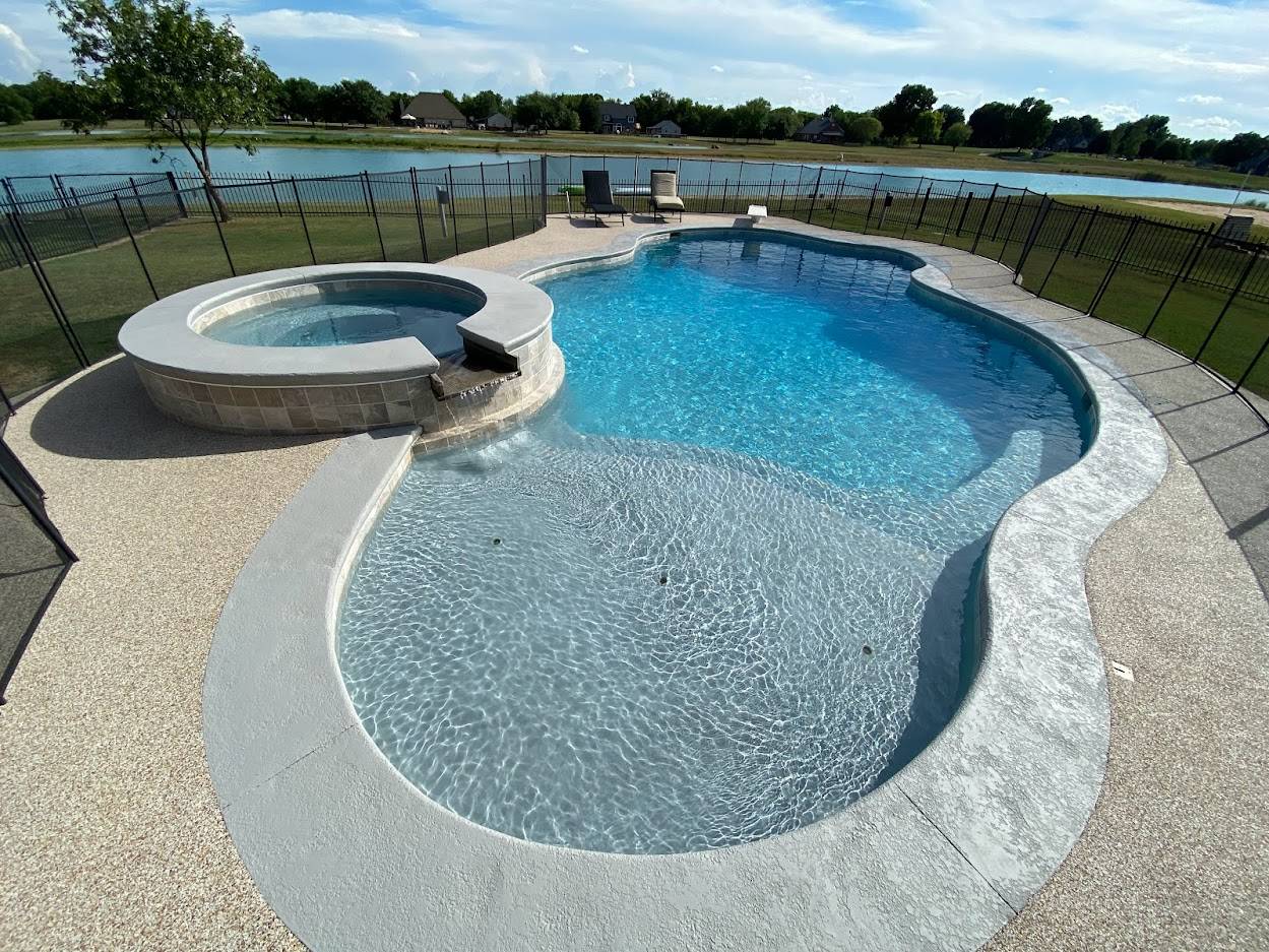 Freeform pool with a raised spillover spa and a safety fence in Mounds, OK