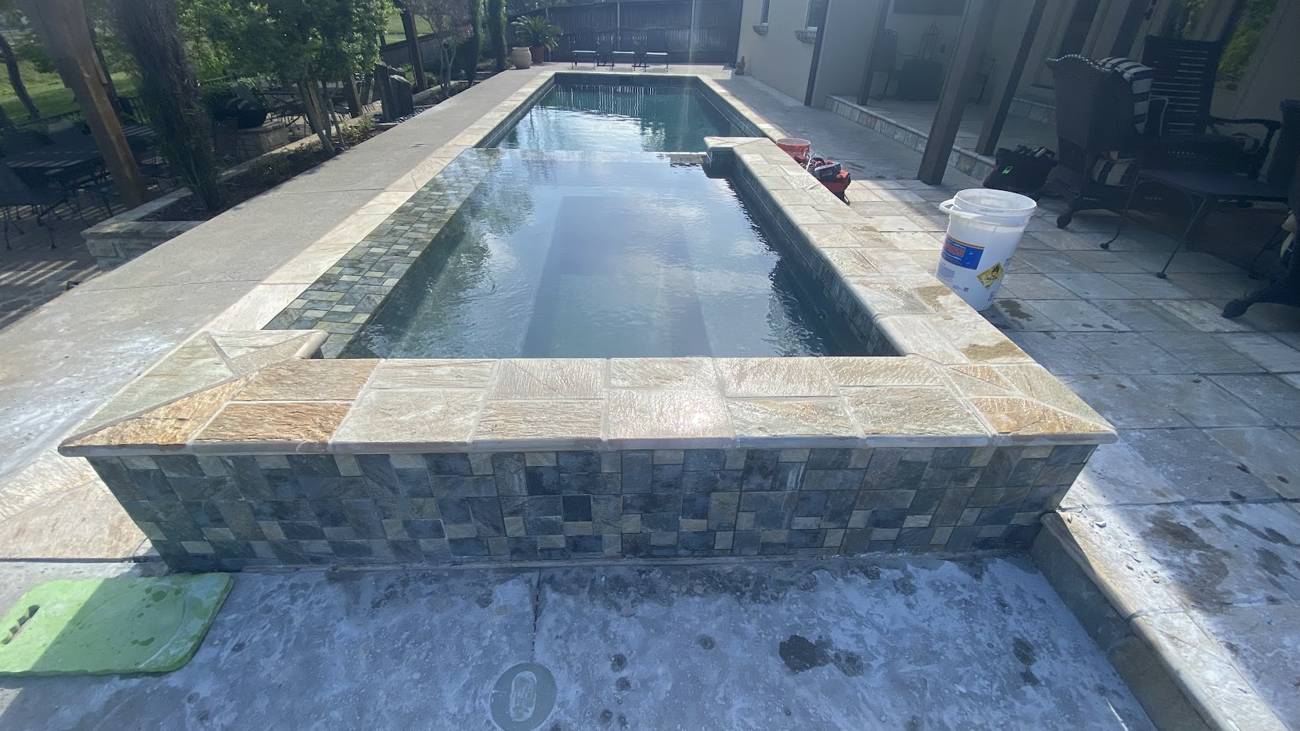 Gunite pool with a raised spa and vanishing edge in Tulsa, OK