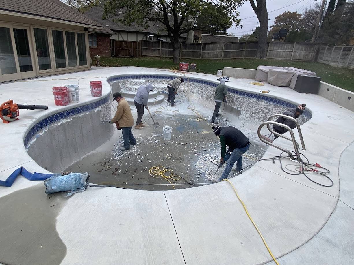 Crew chipping out old plaster during a gunite pool renovation in Tulsa, OK